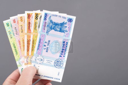 Téléchargez les photos : Monnaie moldave - leu dans la main sur un fond gris - en image libre de droit