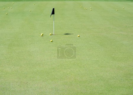 Téléchargez les photos : Différentes balles de golf sur un green dans la zone d'essai avec drapeau - en image libre de droit