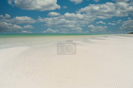 Téléchargez les photos : Une vue panoramique sur une plage tropicale déserte de sable blanc avec un ciel bleu et des nuages blancs, parfaite pour se détendre et se ressourcer. - en image libre de droit