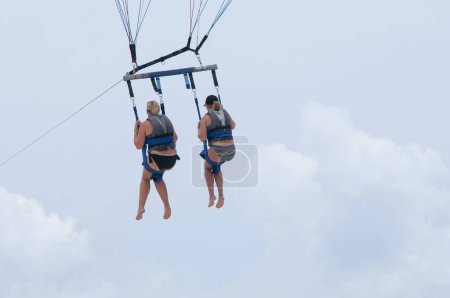Photo for Rear view of two friends parasailing against the blue sky in Mexico - Royalty Free Image