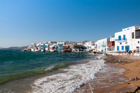 Téléchargez les photos : Vue de la plage les maisons blanches de bord de mer du village de Chora sur l'île de Mykonos en Grèce. En arrière-plan le ciel bleu pendant les vacances d'été. - en image libre de droit