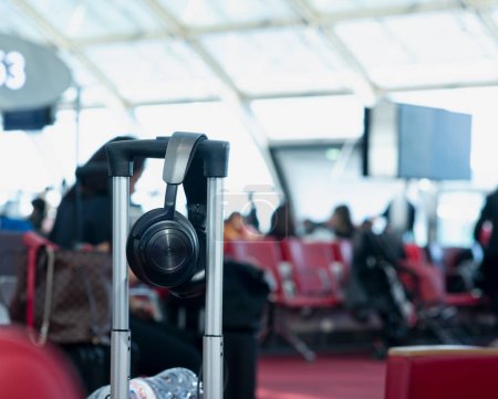 Großaufnahme von Audio-Kopfhörern, die in einem Trolley auf dem internationalen Flughafen von Paris auf das Boarding am Flugsteig warten. Der Hintergrund zeigt verschwommene Sitze und Passagiere. Paris, Frankreich