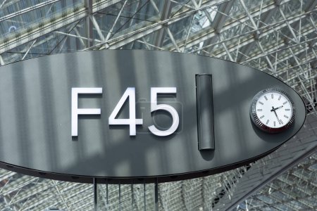 Modernes F45-Flughafenschild mit Uhr, die Gate oder Boarding Door anzeigt, in einer Stahl- und Glaskonstruktion am CDG-Flughafen in Paris, Frankreich
