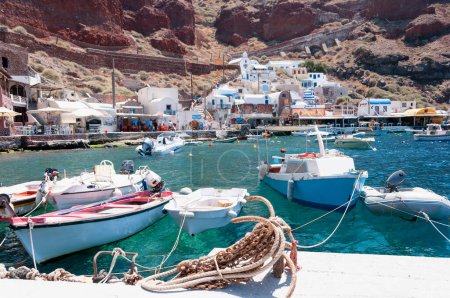 Picturesque port of Ammoudi on the island of Santorini in Greece, with its fishing boats the blue waters and sheer cliffs