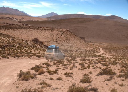 Foto de SUV se mueve a través de los maravillosos paisajes, cielos y montañas mientras cruza el Altiplano en los altos Andes del suroeste de Bolivia - Imagen libre de derechos