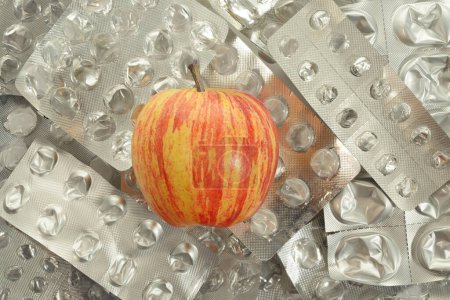 Foto de Una manzana con ampollas de medicamentos vacías. Alimentos saludables frente a la terapia farmacéutica. Vista de la mesa. - Imagen libre de derechos