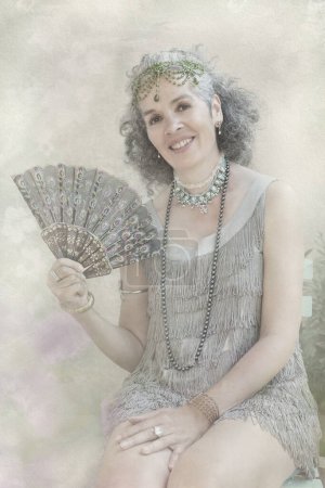 Photo for Portrait of a smiling woman dressed in 1920s style with fringe flapper dress and jewelry. She is holding a fan in one hand. Vintage sepia old stained photo effect. - Royalty Free Image