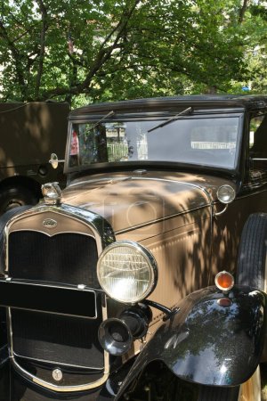 Téléchargez les photos : Vintage Ford Modèle Une automobile de 1931 aux couleurs beige et noir. Vue sur le capot, un phare, la grille de voiture, le logo Ford et la mascotte d'oiseau. - en image libre de droit