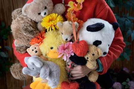 Photo for Unknown person hugging soft toys in various shapes and sizes, flowers and hearts. - Royalty Free Image