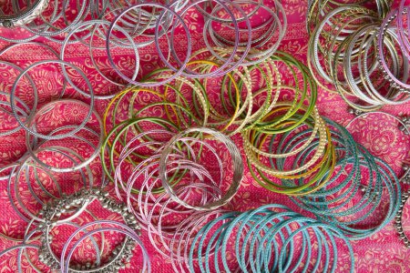 Indian or Pakistani traditional Chura bracelets made out of aluminum or nickel silver. Bangles placed on a colorful textile cloth. 