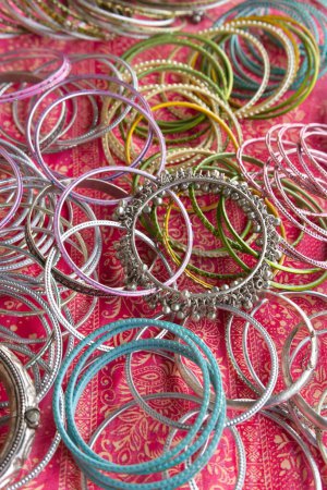 Indian or Pakistani traditional Chura bracelets made out of aluminum or nickel silver. Items placed on a colorful textile cloth.