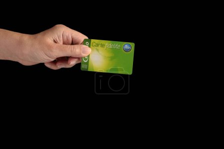 Photo for A hand holding a payback fidelity card from a French supermarket brand. Isolated on a black background, copy space. - Royalty Free Image