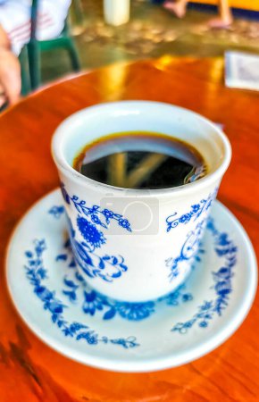 Foto de Taza azul y blanca con café negro americano sobre mesa de madera en El Cafecito en Zicatela Puerto Escondido Oaxaca México. - Imagen libre de derechos