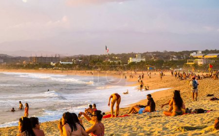 Photo for People are watching beautiful stunning colorful and golden sunset in yellow orange red on beach and big wave panorama in tropical nature in Zicatela Puerto Escondido Oaxaca Mexico. - Royalty Free Image