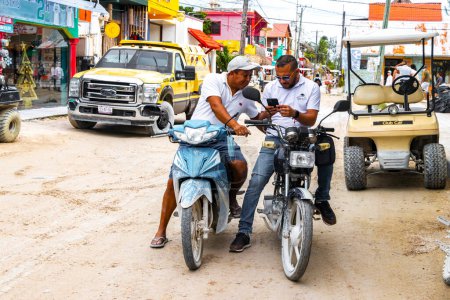 Foto de Two men on motorcycles look into cell phoneon Isla Holbox island in Quintana Roo Mexico. - Imagen libre de derechos