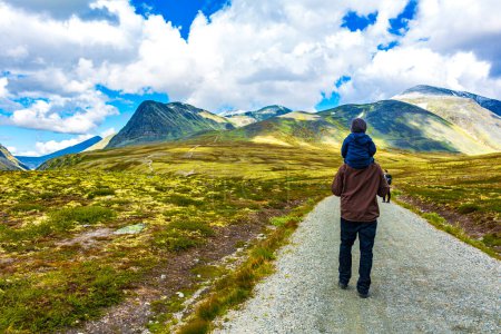 Photo for Man father hiker with child in arms and beautiful summer landscape panorama with mountains river lake rocks and hiking trail of Rondane National Park in Ringbu Innlandet Norway in Scandinavia. - Royalty Free Image