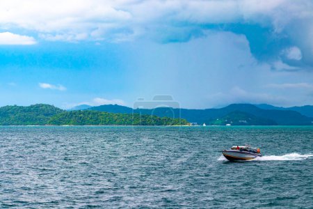 Téléchargez les photos : Voyage en ferry yacht bateau à queue longue et de hautes vagues à travers le paysage tropical panorama sur la plage d'eau turquoise entre les roches calcaires à Ratsada Amphoe Mueang Phuket sur l'île de Phuket en Thaïlande. - en image libre de droit