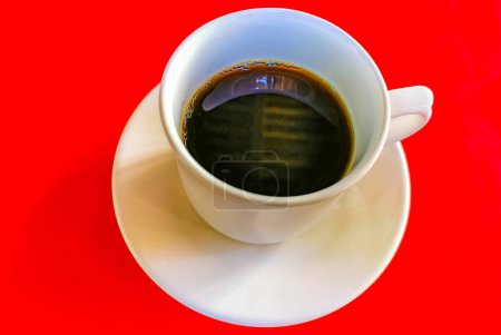 Foto de Taza de café negro americano con cuchara y plato sobre fondo de mesa roja comida y bebida en el restaurante en Zicatela Puerto Escondido Oaxaca México. - Imagen libre de derechos