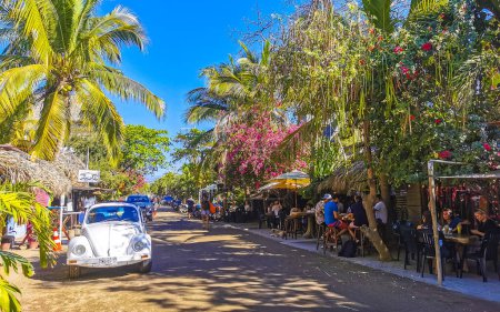 Photo for Puerto Escondido Oaxaca Mexico 27. January 2023 Typical colorful tourist street with people tourist shops stores restaurants cars and bar in La Punta in Zicatela Puerto Escondido Oaxaca Mexico. - Royalty Free Image