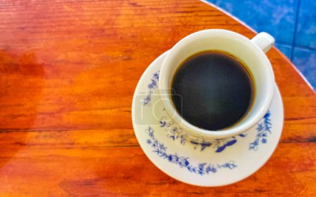 Foto de Taza azul y blanca con café negro americano sobre mesa de madera en El Cafecito en Zicatela Puerto Escondido México. - Imagen libre de derechos
