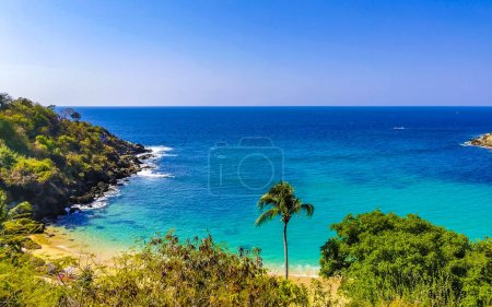 Beach sand turquoise blue water rocks cliffs boulders palm trees huge big surfer waves and panorama view on the beach Playa Carrizalillo in Puerto Escondido Oaxaca Mexico.