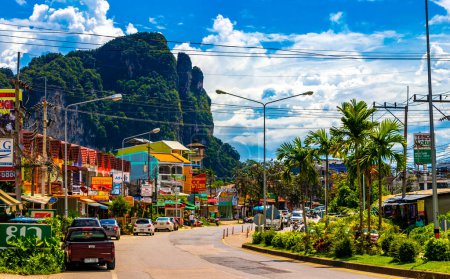 Photo for Ao Nang Krabi Thailand 17. October 2018 Typical colorful street road with people buildings hotels cars vehicles palm trees and limestone rocks mountains in Ao Nang Krabi Thailand in Southeast Asia. - Royalty Free Image