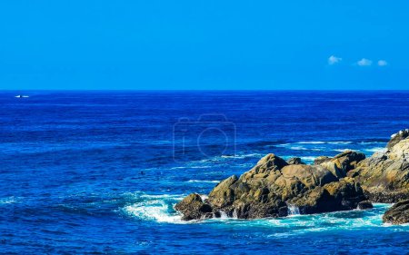 Foto de Agua azul turquesa y extremadamente hermosa olas grandes surfistas rocas acantilados piedras montañas y rocas en la playa en Zicatela Puerto Escondido Oaxaca México. - Imagen libre de derechos