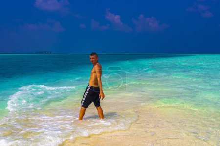 Foto de Hombre modelo masculino y turista divertirse y posar fresco feliz en vacaciones en gradiente de color y banco de arena de las islas Madivaru y Finolhu en Rasdhoo Atolón Maldivas. - Imagen libre de derechos