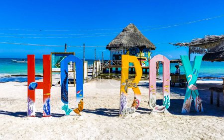 Foto de Holbox Quintana Roo México 21. Diciembre 2021 Coloridas cartas de bienvenida y un cartel en el hermoso banco de arena de la isla Holbox y la playa con olas de agua turquesa y cielo azul. - Imagen libre de derechos