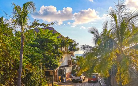 Photo for Puerto Escondido Oaxaca Mexico 02. October 2022 Typical beautiful colorful tourist street road and sidewalk with city life cars traffic buildings hotels bars restaurants and people in Zicatela Mexico. - Royalty Free Image