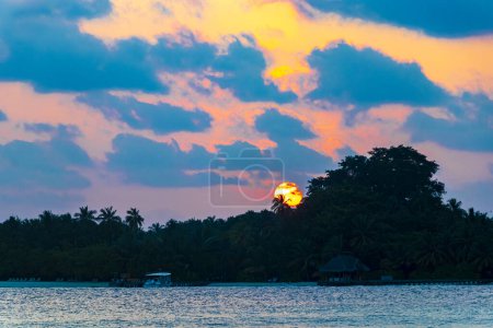 Foto de Isla paradisíaca tropical Kuramathi para vacaciones de lujo con palmeras de arena blanca aguas turquesas e increíble puesta de sol de colores dorados en el atolón Rasdhoo Maldivas. - Imagen libre de derechos