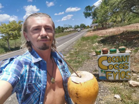 Foto de Hombre Hombre turista con coco en el puesto de coco bebiendo coco en Chiquila Lazaro Cárdenas en Quintana Roo México. - Imagen libre de derechos