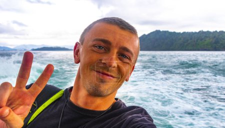 Téléchargez les photos : Homme beau touriste masculin sur un ferry pour Ao Nang à Ratsada Amphoe Mueang Phuket sur l'île de Phuket Thaïlande en Asie du Sud-Est. - en image libre de droit