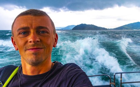 Téléchargez les photos : Homme beau touriste masculin sur un ferry pour Ao Nang à Ratsada Amphoe Mueang Phuket sur l'île de Phuket Thaïlande en Asie du Sud-Est. - en image libre de droit