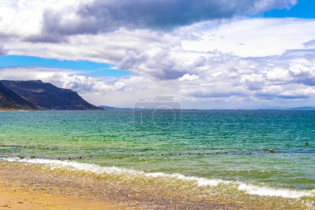 Long Beach with turquoise blue water mountains landscape panorama view and blue sky with clouds in Simons Town Cape Town Capetown Western Cape South Africa Southafrica.