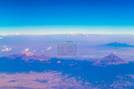 Flying in an airplane over Mexico Clouds Sky Volcanoes Mountains City and desert in Mexico.