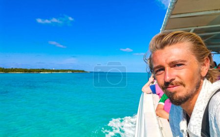 Handsome male tourist person man traveler takes selfie photo at amazing landscape panorama turquoise blue water palm trees blue sky the natural tropical beach and forest on the beautiful island of Contoy Mexico.