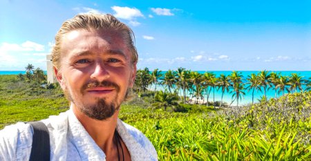 Schöne männliche Touristenperson Mann Reisender macht Selfie-Foto bei erstaunlichen Landschaft Panorama türkisblauen Wasserpalmen blauer Himmel der natürliche tropische Strand und Wald auf der schönen Insel Contoy Mexiko.