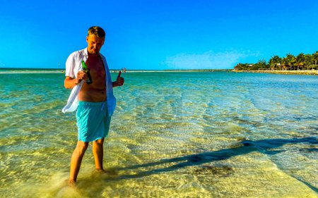 Foto de Hombre atractivo y atractivo turista toma foto selfie con vista panorámica del paisaje en el hermoso banco de arena de la isla Holbox y la playa con olas de agua turquesa y cielo azul en México. - Imagen libre de derechos