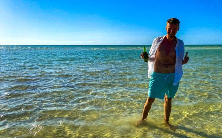Foto de Hombre atractivo y atractivo turista toma foto selfie con vista panorámica del paisaje en el hermoso banco de arena de la isla Holbox y la playa con olas de agua turquesa y cielo azul en México. - Imagen libre de derechos