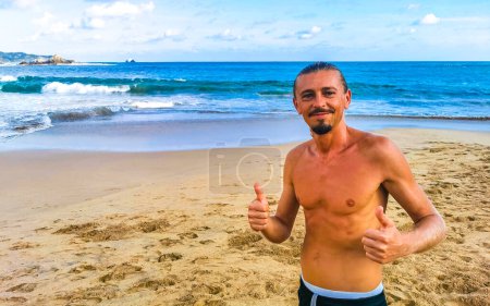 Photo for Handsome male tourist and traveler at tropical beach with sand waves rocks mountains cliffs in Mazunte Oaxaca Mexico. - Royalty Free Image