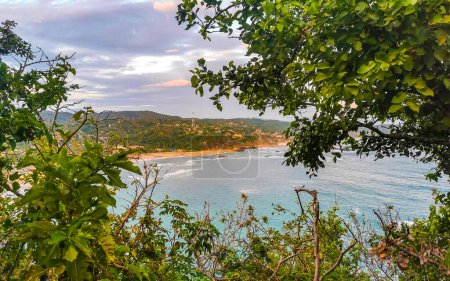 Punta Cometa and Playa Mazunte sunset beach panorama view with waves cliff cliffs mountain mountains hill hills rocks rock in tropical nature jungle forest in Mazunte Oaxaca Mexico.