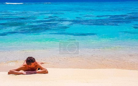 Foto de Hombre acostado en la playa arena y agua en la playa tropical en la isla Rasdhoo en el atolón Rasdhoo Maldivas. - Imagen libre de derechos