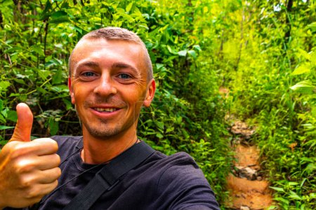 Handsome male tourist man at tropical jungle and forest hiking trails through nature to the mountain peak in Chiang Mai Amphoe Mueang Chiang Mai Thailand in Southeastasia Asia.