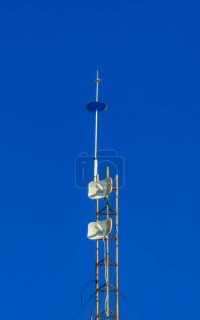 Red white 5G tower with blue sky background radiation kills us in Zicatela Puerto Escondido Oaxaca Mexico.