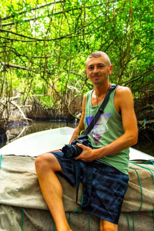 Jeune homme touriste avec caméra prenant des photos sur le safari en bateau à travers la forêt de la jungle de mangroves dans le lac de la rivière Bentota Ganga à Bentota Beach Sri Lanka.