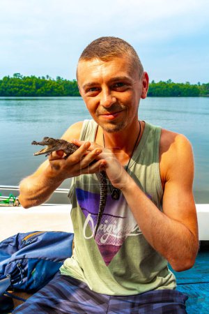 Man tourist with baby crocodile alligator in his hands at Bantota Ganga river in Bentota Beach Galle District Southern Province Sri Lanka.