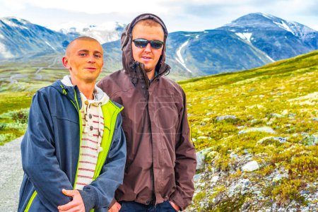 Young male hiker men friends and beautiful summer landscape panorama with mountains river lake rocks and hiking trail of Rondane National Park in Ringbu Innlandet Norway in Scandinavia.