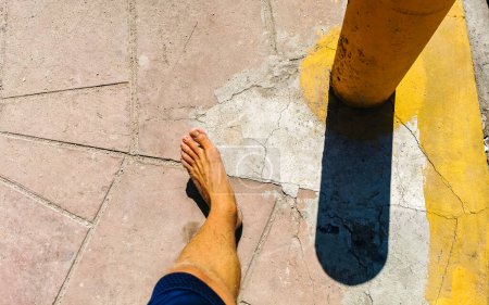 Caminando sobre el pavimento piedras pies descalzos en Zicatela Puerto Escondido Oaxaca México.