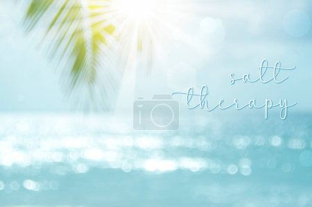 Weich fokussierte Meereslandschaft mit Palmwedel im Vordergrund, Sonne, die das Licht auf dem Wasser bricht, Bokeh-Lichteffekte + "Salztherapie"